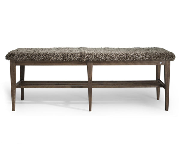 Bänk med grå fårskinnsdyna och mörkt träunderrede med hylla