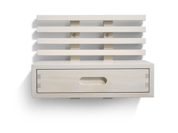 Väggmonterad sänghylla i ljust trä med ribbor och en utdragbar låda med oval handtagsöppning