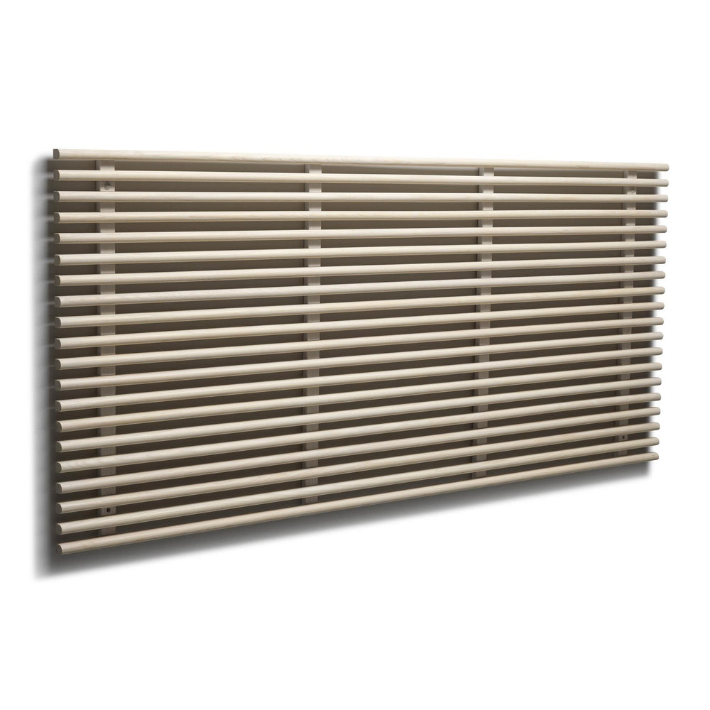 Horisontell designradiator med runda rör i beige/sandfärg monterad på vit vägg