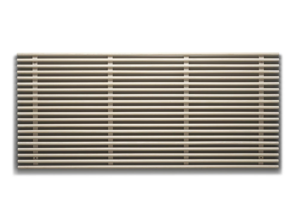 Horisontell designradiator med runda rör i beige/sandfärg monterad på vit vägg