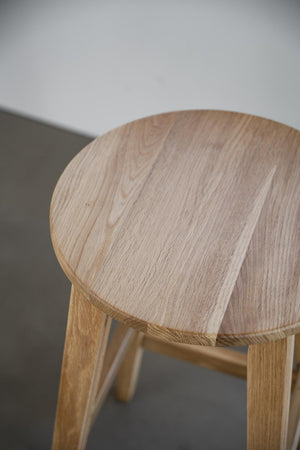 Rund träpall i ljus ek med synlig årring och naturlig trästruktur, närbild av sitsen