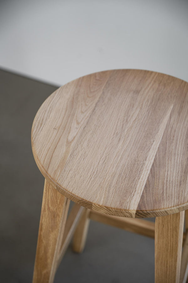 Rund träpall i ljus ek med synlig årring och naturlig trästruktur, närbild av sitsen