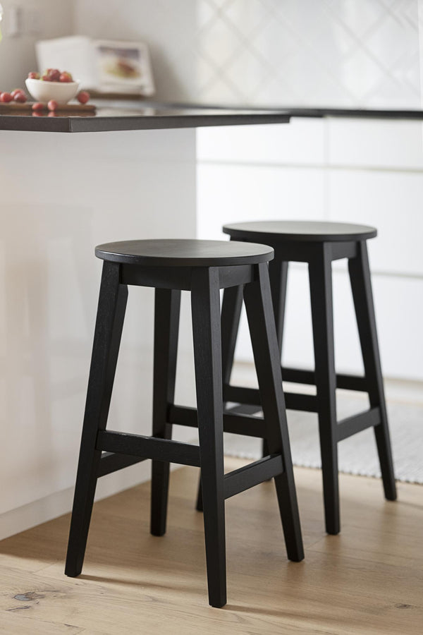 Två svarta träpallar vid vitt köksbord i modern skandinavisk inredning