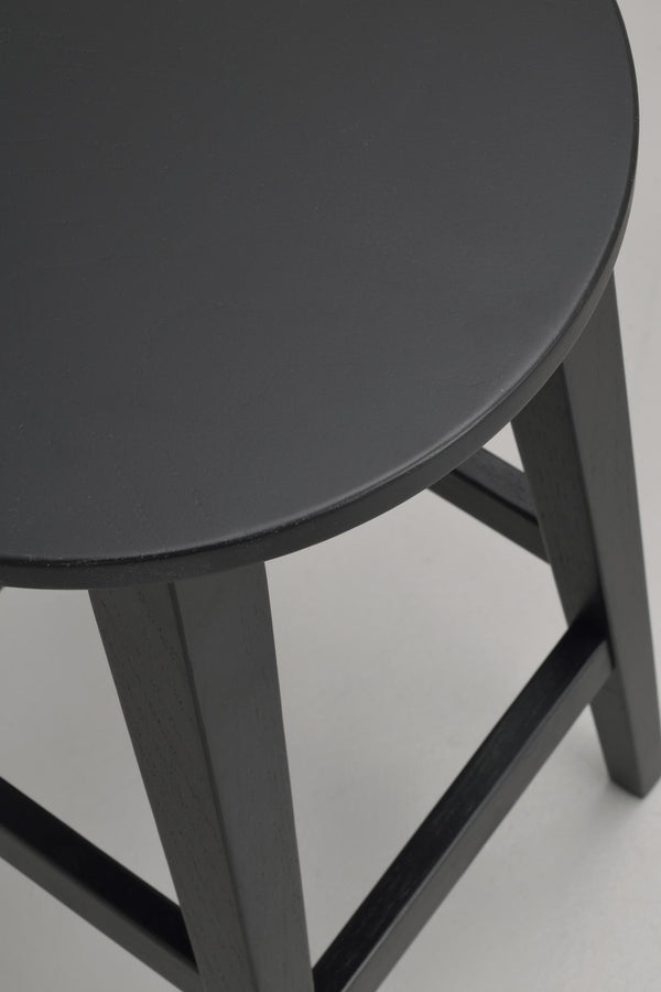 Närbild på rundad sits och ben på mörkgrå pall eller barstol med träkonstruktion