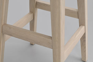 Träpall med ljust trä och krysstöd mellan benen, närbildsdetalj av konstruktionen