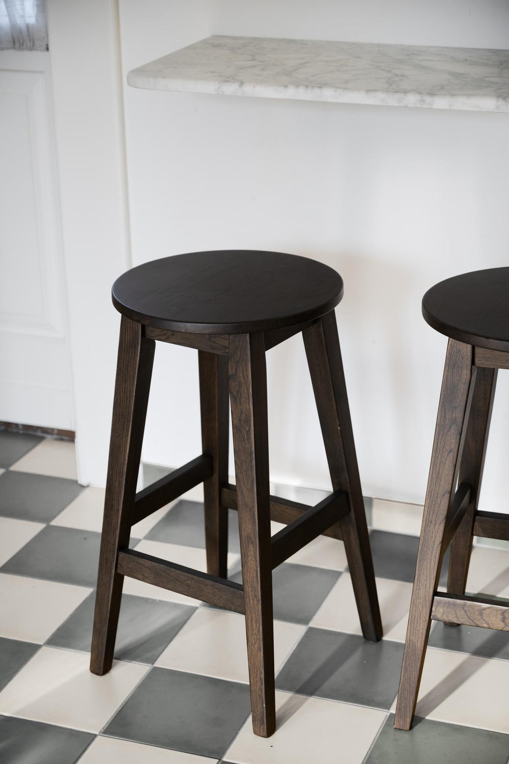 Rund barpall i mörkbrun ek med fyra ben och fotstöd