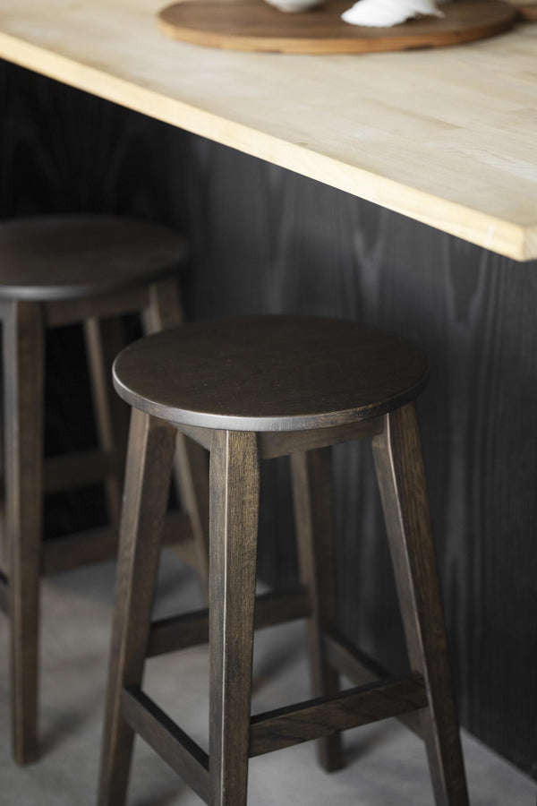 Mörkbrun trästol under köksö med ljus träskiva och svart front i modernt kök