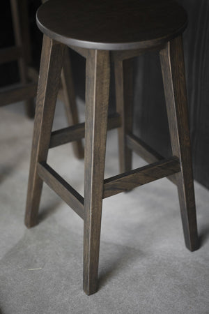 Rund pallar i mörkbetsad ek med fyra ben och förstärkande ribbor, skandinavisk design