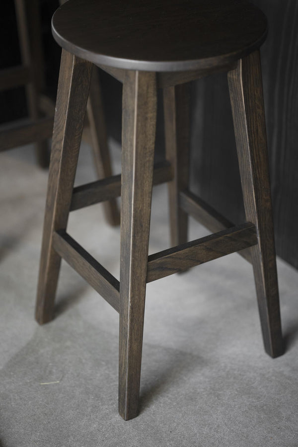 Rund pallar i mörkbetsad ek med fyra ben och förstärkande ribbor, skandinavisk design