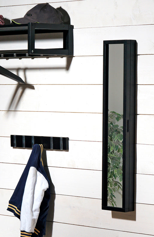 Svart spegel med förvaring och krokpanel monterad på vit vägg i hall, med jacka upphängd