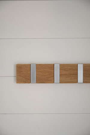 Väggkrok i ek och aluminium med tre krokar monterad på vit vägg