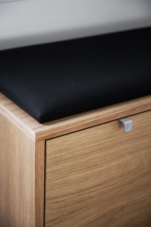 Hallbänk i ekfanér med svart sits och diskret metallhandtag på låda