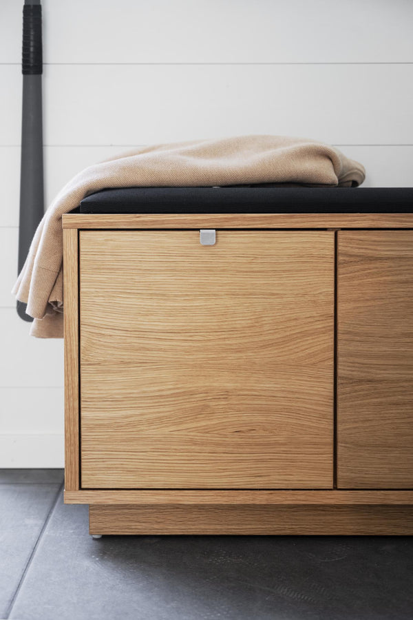 Hallbänk i ekfanér med svart stoppning och beige filt, modern förvaring med dörr och metallhandtag