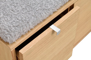 Öppen låda i ljust trä med vit metallhandtag och grå fuskpäls ovanpå