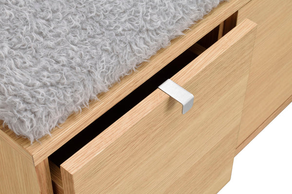 Öppen låda i ljust trä med vit metallhandtag och grå fuskpäls ovanpå