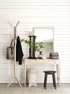 Hallmöbler i ljust trä med spegelbord, klädhängare, pall och dekorationer mot vit panelvägg