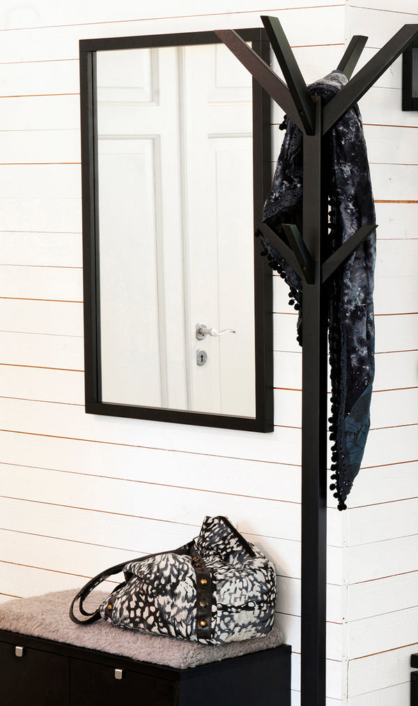 Svart hallmöbel med spegel, klädhängare och sittbänk med pälsfodral och väska i vit hall