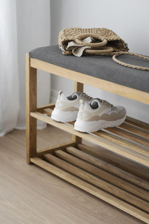 Hallbänk i ljust trä med grå dyna, skoförvaring och vit sneakers på hylla, dekorerad med väska