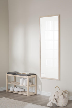 Hallspegel med ljus träram ovanför bänk med skohylla och grå dyna i minimalistisk entré
