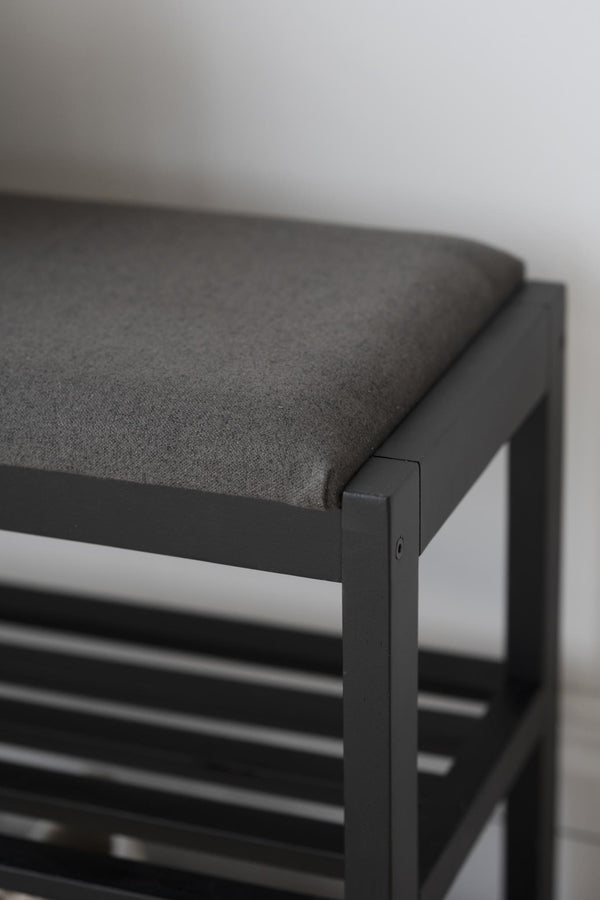 Grå sits med svart metallram på pall med skoförvaring, närbild av hörn och konstruktion