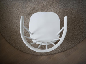 Vit stol uppochned på rund jutematta, ovanifrån fotograferad med synliga ben och sits