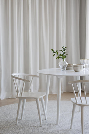 Vit rund matbord med två matchande trästolar i skandinavisk design, dekorerat med vas och skålar