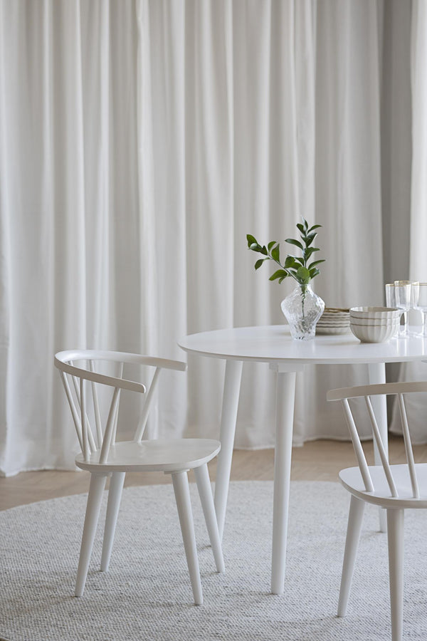Vit rund matbord med två matchande trästolar i skandinavisk design, dekorerat med vas och skålar