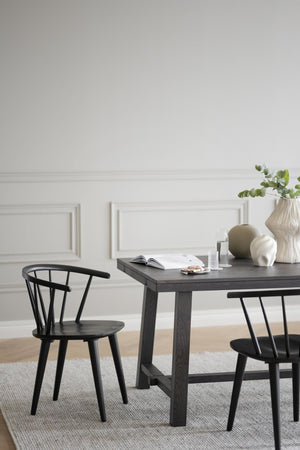 Svart matbord i trä med matchande pinnstolar och dekorativa vaser i skandinavisk stil