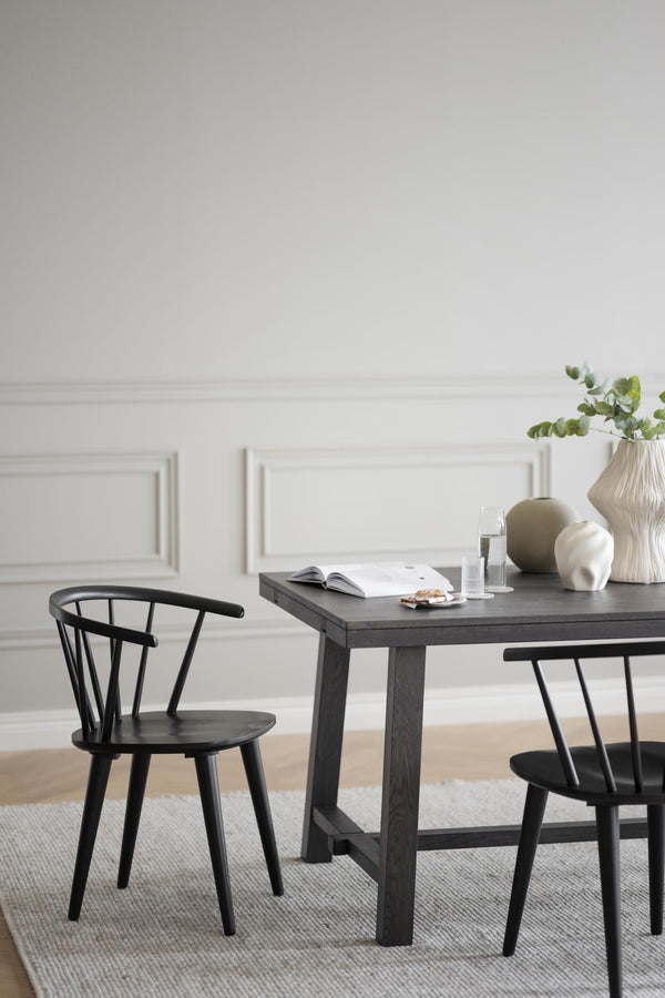 Svart matbord i trä med matchande pinnstolar och dekorativa vaser i skandinavisk stil