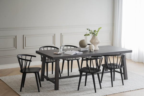 Svart matbord med sex matchande pinnstolar i modern skandinavisk stil på ljus matta