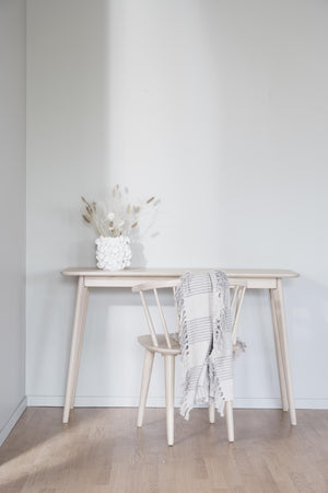 Ljust träskrivbord med matchande stol, dekorerad med vit vas och grästorkar i minimalistisk skandinavisk stil