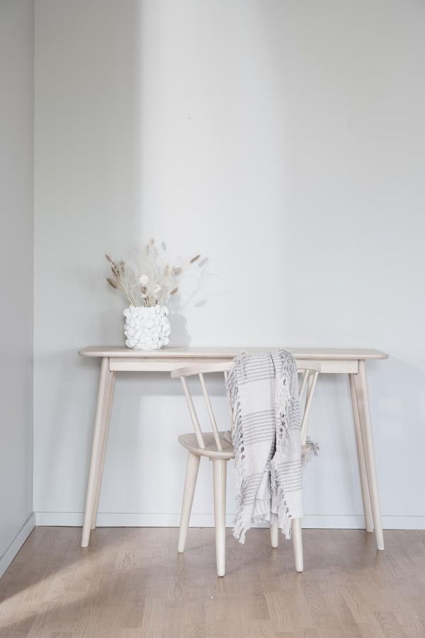 Ljust träskrivbord med matchande stol, dekorerad med vit vas och grästorkar i minimalistisk skandinavisk stil