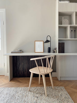 Ljust hemmakontor med vit skrivbordslåda, ljus trästol och inbyggd förvaring med ribbad design