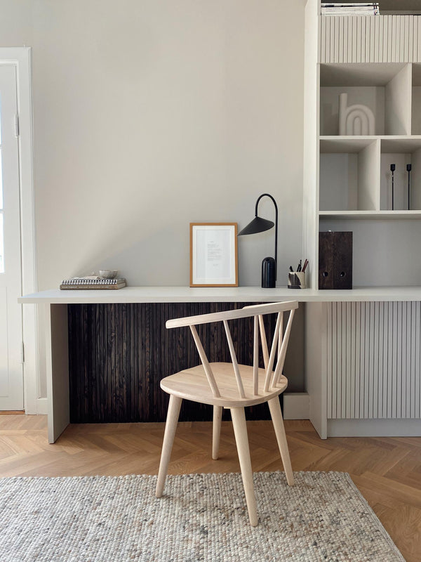 Ljust hemmakontor med vit skrivbordslåda, ljus trästol och inbyggd förvaring med ribbad design
