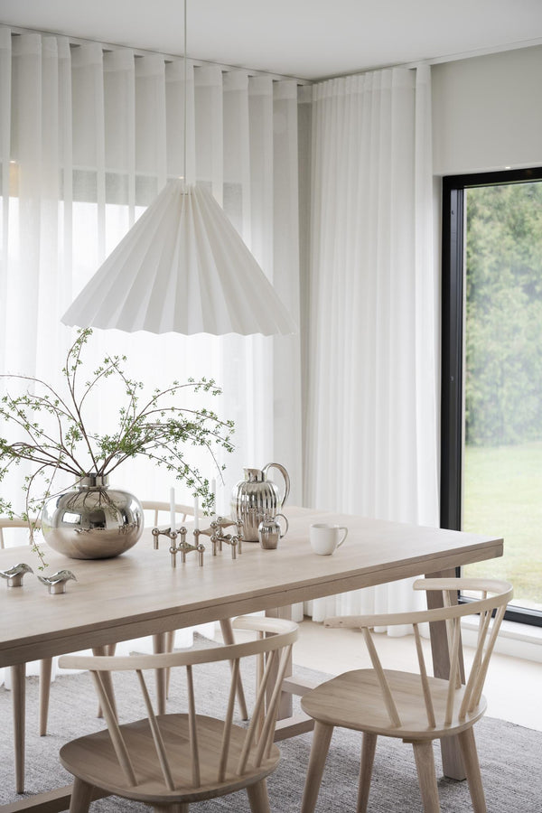 Minimalistisk matplats med ljust trämöbler, vit plisserad taklampa och vita genomskinliga gardiner