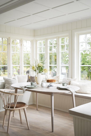 Ljus matplats med panoramafönster, built-in sittbänk, runt matbord i trä och skandinaviska stolar