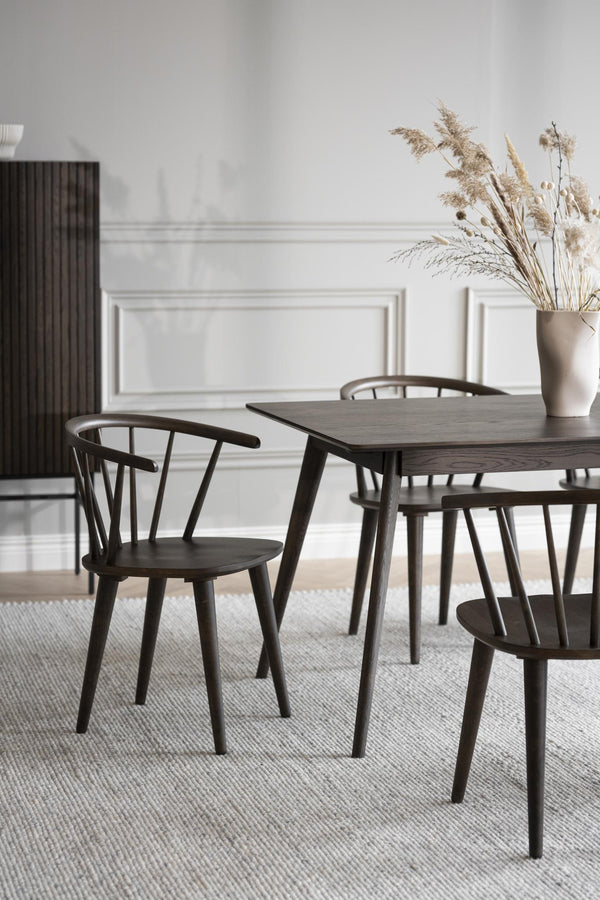 Mörkt matbord i trä med matchande stolar i skandinavisk design, dekorerat med torkade blommor i vas