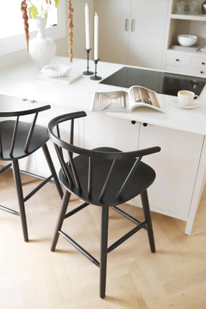 Svarta barstolar med ryggstöd vid vit köksbänk i skandinavisk minimalistisk stil