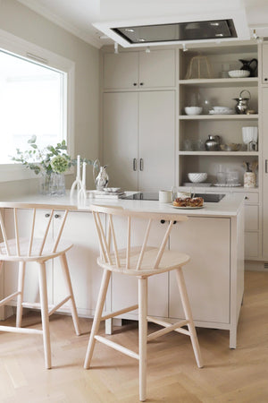 Ljust kök med köksö, barstolar i trä och öppna hyllor med vitserviser i skandinavisk stil