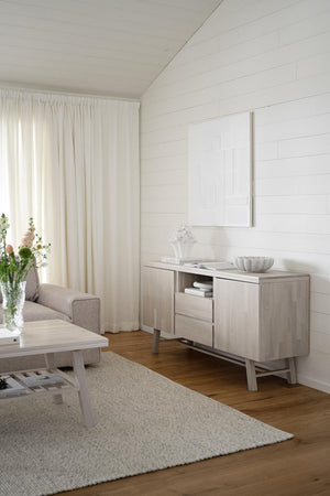 Ljust vardagsrum med vit skänk, beige matta, gardiner och shiplap-vägg i skandinavisk stil