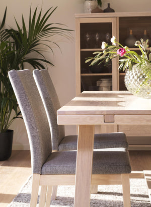 Matbord i ljust trä med grå stoppade stolar och glasskåp i modern skandinavisk stil