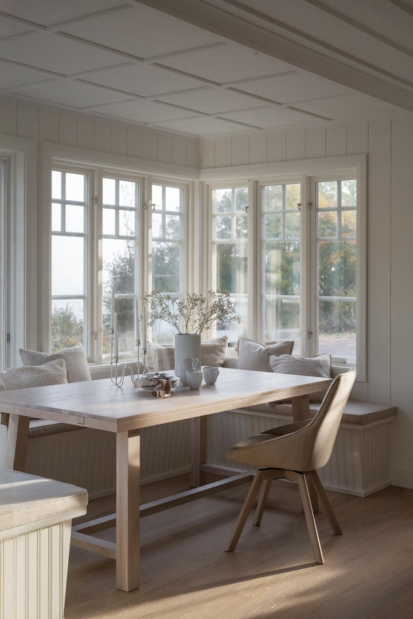 Ljus matplats med träbord, stol och bänk vid fönster med utsikt, skandinavisk inredning i neutrala toner