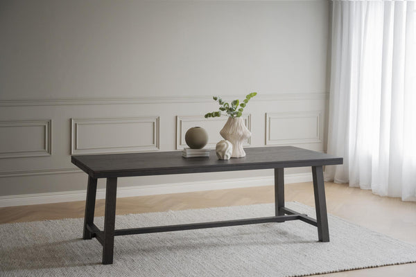 Matbord i mörkgrått trä med svarta ben i modern skandinavisk design på ljus matta i vardagsrum