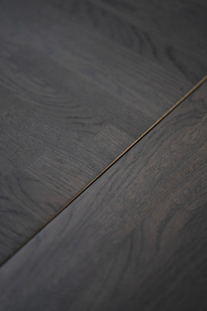 Mörkgrå ekparkettgolv med synlig trästruktur och fog mellan plankorna