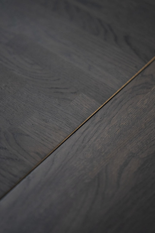 Mörkgrå ekparkettgolv med synlig trästruktur och fog mellan plankorna