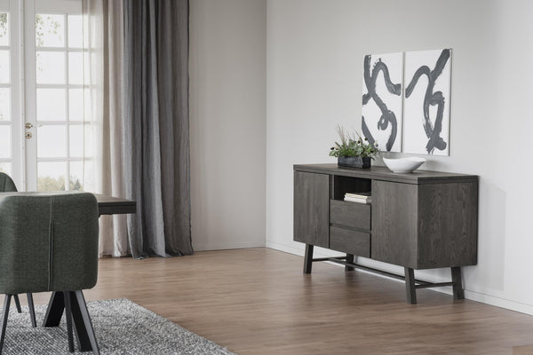 Grått skänkskap i modern skandinavisk stil placerat mot vit vägg i ljust vardagsrum med trägolv