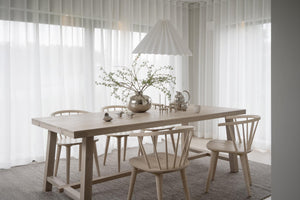 Ljus matplats med träbord, pinnsoffor och vita gardiner i skandinavisk stil