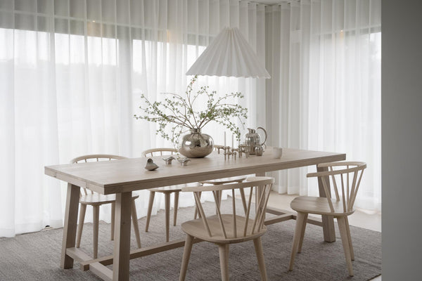 Ljus matplats med träbord, pinnsoffor och vita gardiner i skandinavisk stil