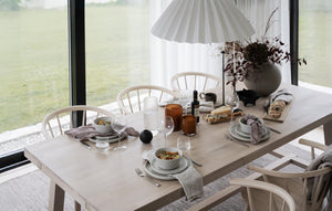 Ljus matplats med träbord, stolar, pendellampor och vacker bordsdukning i skandinavisk stil