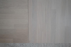 Ljusgrå trägolv med synlig struktur och foder, närbild på laminat- eller parkettplankor
